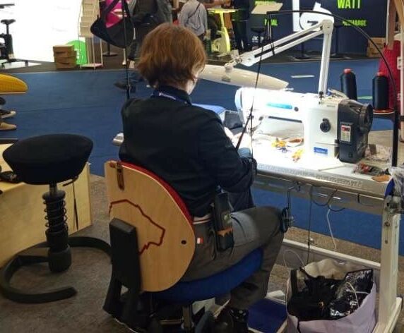 Mise en situation sur un poste de couture équipé d’un siège et de dispositifs de soutien des bras.